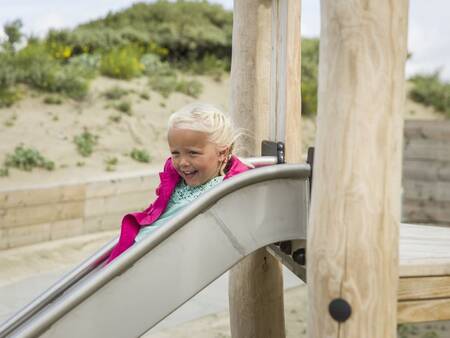 Kindje op de glijbaan in de speeltuin van Roompot Beach Villa’s Hoek van Holland