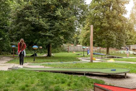 Vrouw op de midgetgolfbaan op vakantiepark Roompot Bospark Lunsbergen
