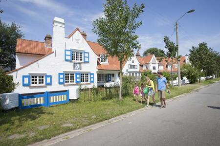 Een gezin wandelt langs vakantiehuizen op vakantiepark Roompot Breeduyn Village