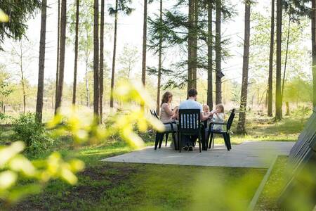 Gezin aan het eten in de tuin van een vakantiehuis op Roompot Bungalowpark Hoenderloo