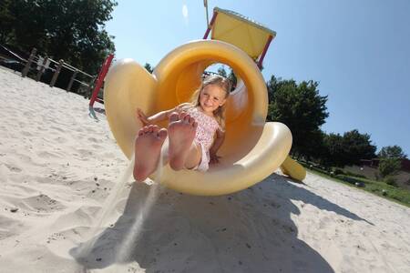 Kind op de glijbaan in de speeltuin van vakantiepark Roompot Bungalowpark Schin op Geul