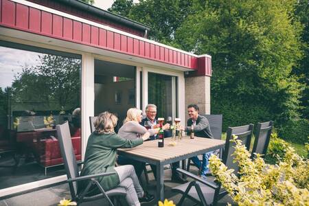 Mensen drinken een drankje op het terras bij een vakantiehuis op Roompot Bungalowpark Schin op Geul