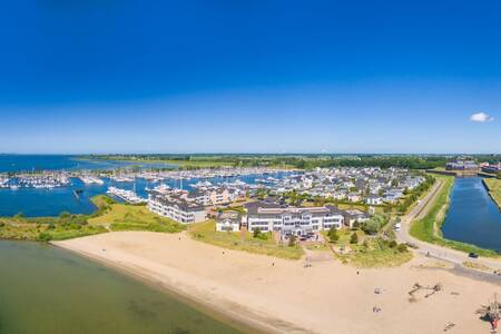 Luchtfoto van vakantiehuizen op vakantiepark Roompot Cape Helius en de jachthaven
