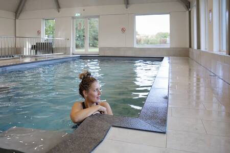 Een vrouw zwemt in het binnenbad van vakantiepark Roompot De Heihorsten