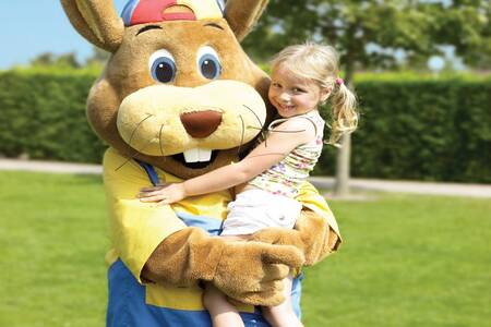 Meisje wordt opgetild door Koos konijn op vakantiepark Roompot De Katjeskelder