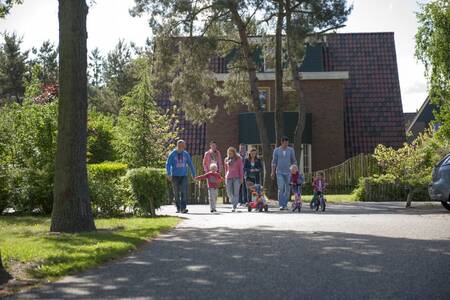 Gezin wandelt tussen de vakantiehuizen op vakantiepark Roompot De Katjeskelder