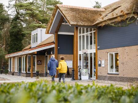 2 mensen wandelen voor het centrumgebouw Roompot De Veluwse Hoevegaerde