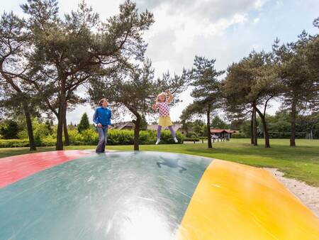 2 kinderen springen op de airtrampoline in de speeltuin op Roompot De Veluwse Hoevegaerde