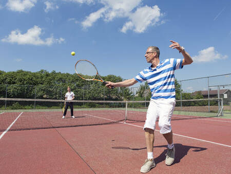 2 mensen tennissen op de tennisbaan van vakantiepark Roompot De Veluwse Hoevegaerde