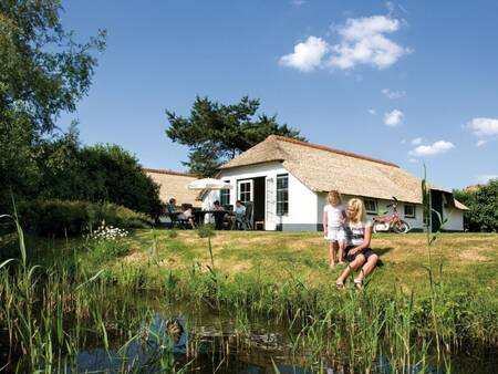 Mensen aan het water bij hun vakantiehuis op vakantiepark Roompot De Veluwse Hoevegaerde