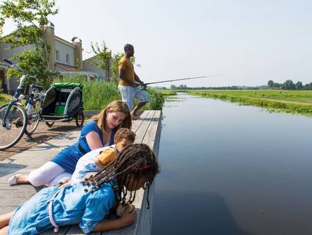 Vissende mensen bij vakantiehuizen aan het water op vakantiepark Roompot Duinresort Dunimar