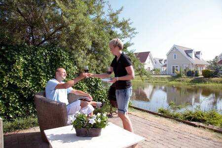 Mensen in de tuin aan het water van een woning op Roompot Duynparc De Heeren van ‘s-Gravensande