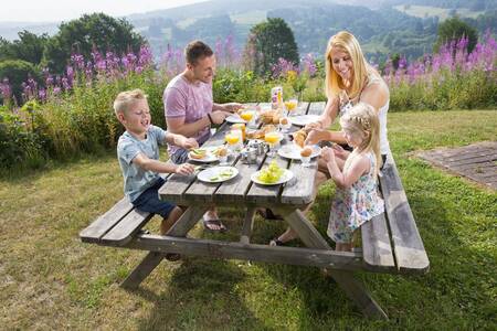 Mensen aan een picknicktafel in de tuin van een vakantiehuis op Roompot Eifelpark Kronenburger See