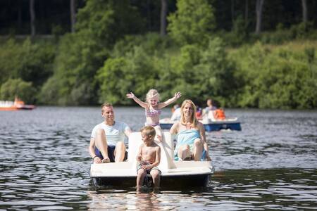 Een gezin op een waterfiets op het meer naast Roompot Eifelpark Kronenburger See
