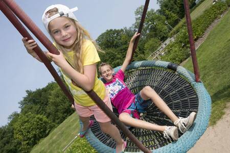 Kinderen op een schommel in de speeltuin op vakantiepark Roompot Ferienresort Bad Bentheim