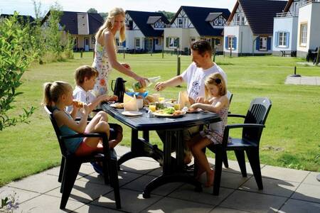 Gezin eet op het terras van een vakantiehuis op Roompot Ferienresort Cochem