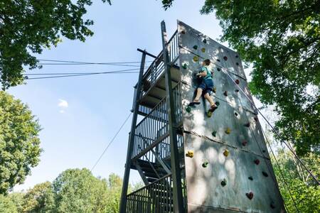 Jongen aan het klimmen op de klimtoren van vakantiepark Roompot Hunzepark
