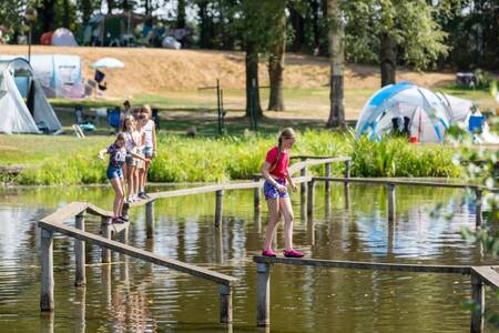 Kinderen op een evenwichtsbalk over het water op vakantiepark Roompot Hunzepark