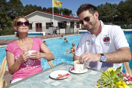 Mensen op het terras bij het buitenbad van vakantiepark Roompot Kustpark Egmond aan Zee