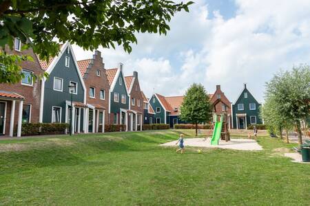 Kinderen spelen in een speeltuin tussen vakantiehuizen op vakantiepark Roompot Marinapark Volendam