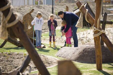 Gezin golft op de minigolfbaan op vakantiepark Roompot Noordzee Résidence Cadzand-Bad