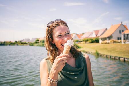 Vrouw eet een ijsje voor vakantiehuizen op Roompot Noordzee Résidence Cadzand-Bad