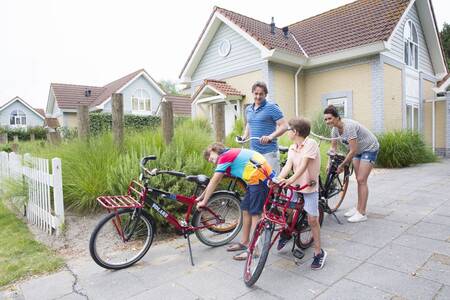 Gezin met fietsen voor een vakantiehuis op Roompot Noordzee Résidence De Banjaard