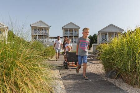 Gezin wandelt tussen helmgras bij vakantiehuizen op Roompot Noordzee Résidence De Banjaard