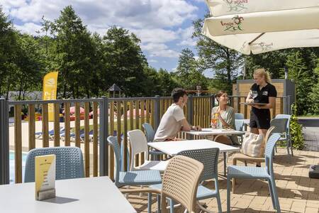 Stel op het terras bij het zwembad op vakantiepark Roompot Parc la Clusure