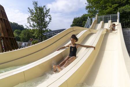 Kinderen glijden van de grote glijbaan in het zwembad van vakantiepark Roompot Parc la Clusure