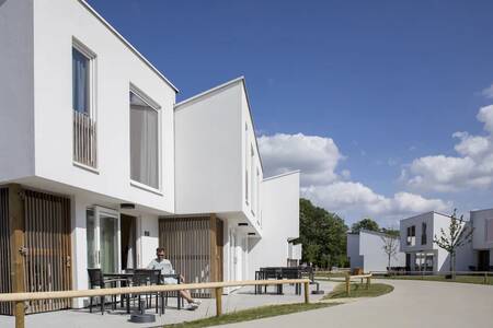 Een man op een terras van een vakantiehuis op vakantiepark Roompot Park Eksel