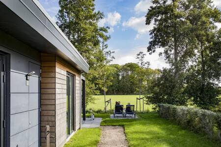 Mensen zitten in de tuin bij hun vakantiehuis op vakantiepark Roompot Park Wijdenes