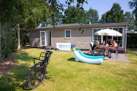 Mensen aan tafel in de tuin van een chalet op vakantiepark Roompot Recreatiepark de Tolplas