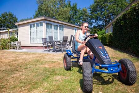 Kind op een skelter in de tuin van een chalet op vakantiepark Roompot Recreatiepark de Tolplas