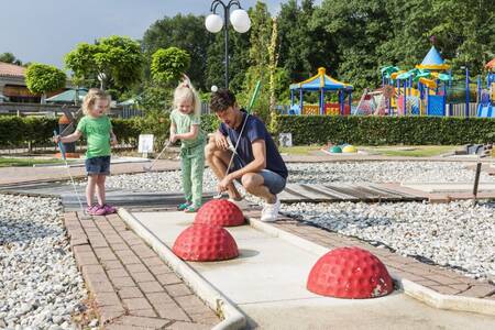 2 kinderen samen met hun vader op de minigolfbaan van vakantiepark Roompot Resort Arcen