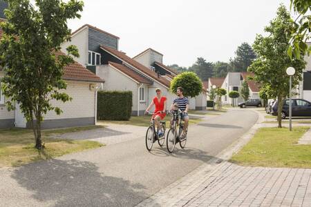 Een gezin fietst tussen vakantiehuizen op vakantiepark Roompot Resort Arcen