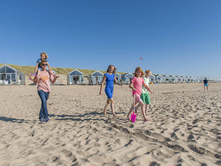 Mensen wandelen op het strand voor strandhuizen op Roompot Strandhuisjes Julianadorp