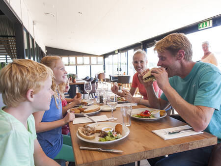 Gezin aan het eten bij een strandpaviljoen nabij Roompot Strandhuisjes Julianadorp