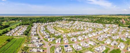 Luchtfoto van vakantiepark Roompot Strandpark Duynhille met de Noordzee aan de horizon