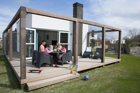 Mensen op de veranda van een vakantiehuis op vakantiepark Roompot Strandpark Duynhille