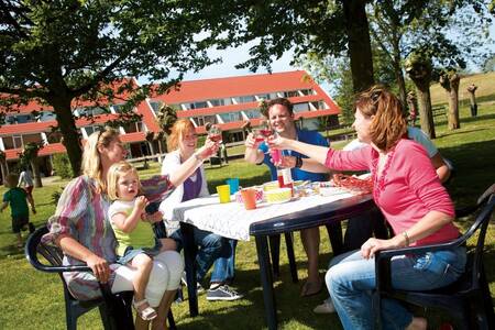 Gezin op een terras voor een appartementencomplex op Roompot Vakantiepark Aquadelta