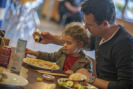 Gezin eet pannenkoeken in een restaurant op Roompot Vakantiepark Aquadelta