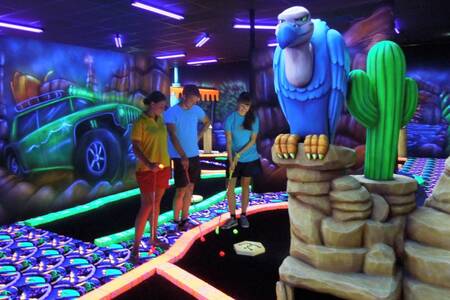 Gezin aan het golfen op de Glow in the dark minigolfbaan van Roompot Vakantiepark Weerterbergen