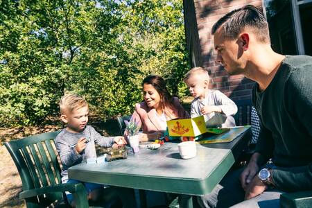 Gezin aan tafel in de tuin van een vakantiehuis op Roompot Vakantiepark Weerterbergen