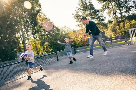 Vader voetbalt samen met 2 kinderen op een voetbalveld op Roompot Vakantiepark Weerterbergen
