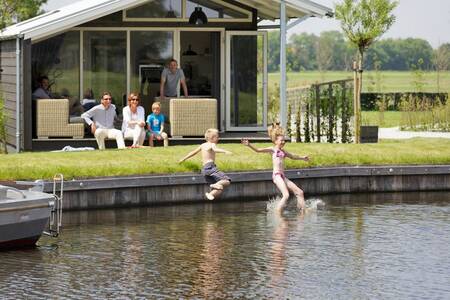 Mensen in de tuin van een vakantiehuis op vakantiepark Roompot Waterpark Terkaple