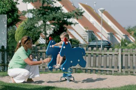 Moeder met een kind in de speeltuin op vakantiepark Roompot Zeeland Village
