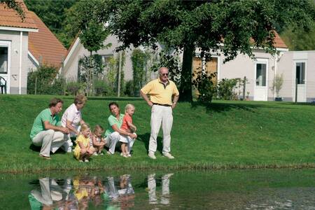 Mensen aan het vissen met daarachter vakantiehuizen op vakantiepark Roompot Zeeland Village