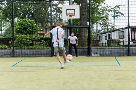 Jongens voetballen op het sportveld van vakantiepark Topparken Bospark Ede