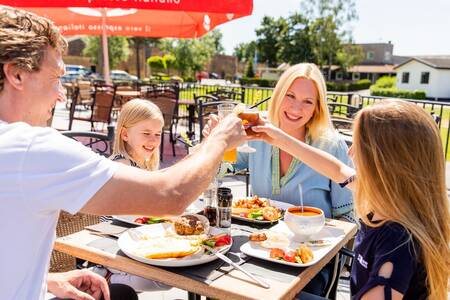 Gezin aan het eten op het terras van het restaurant op vakantiepark Topparken Parc de IJsselhoeve